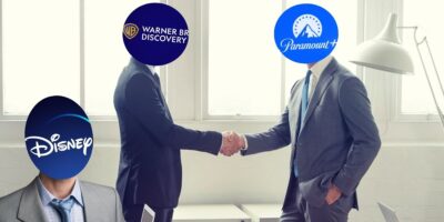 Two men shaking hands in a business meeting with another man popping up in the corner.