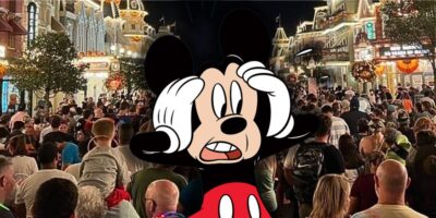 Mickey Mouse with his hands on his head in disbelief with a large crowd at Disney World.