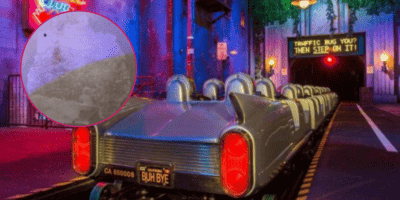 A blurred image of a damaged wall is in the foreground of a wide shot of Rock n Rollercoaster before it shoots off into the dark.
