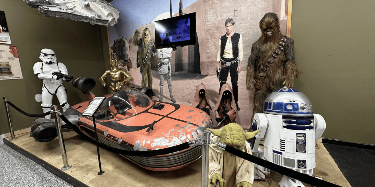 Multiple 'Star Wars' props, including a spaceship, Stormtrooper, and R2-D2 are on display.