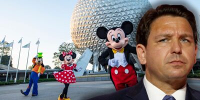 Florida Governor Ron DeSantis looking angry and jealous at Mickey Mouse inside of EPCOT at Disney World.