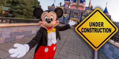Mickey Mouse inside of Disneyland Park in California with a "Under Construction" sign.