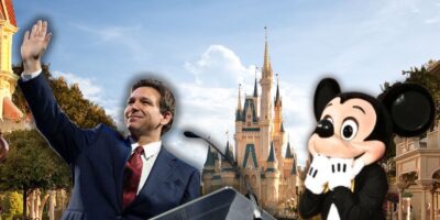 Ron DeSantis on a podium inside of Disney World as Mickey Mouse looks in shock.