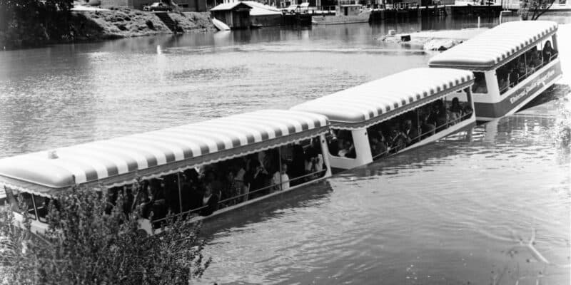 A vintage photograph of passengers enjoying a scenic boat tour at Universal Studios, cruising along a calm waterway with the tranquility of riverside views.