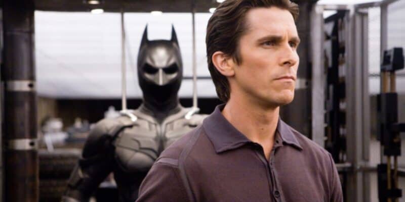 Bruce Wayne (Christian Bale) looking into the distance in front of the Bat suit in 'The Dark Knight'