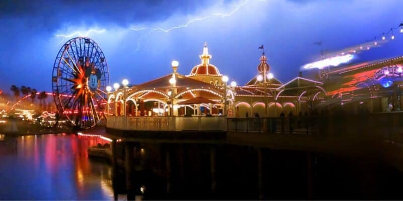 A striking image of Disneyland at night featuring a lit-up carousel and Ferris wheel, with a dramatic lightning bolt illuminating the sky in the background.