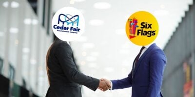 The official Six Flags logo and the official Cedar Fair logo as men shaking hands.