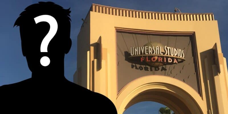 Visitor silhouetted against the iconic archway entrance of Universal Studios Florida with Labbie the Cabbie on a sunny day.
