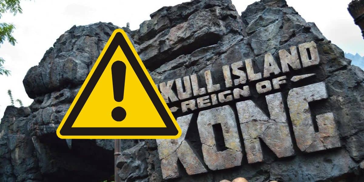 Image of a rock facade with the words "skull island: reign of kong" in bold, stylized letters, symbolizing an adventurous theme park attraction. a warning symbol overlays part of the image.