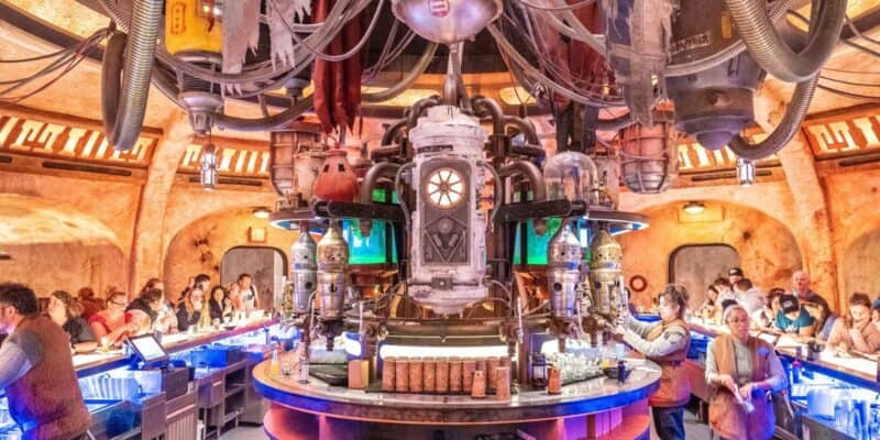 A bustling, futuristic bar teeming with patrons, centered around an intricate, mechanical contraption that adds to the immersive, otherworldly ambiance.