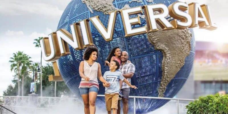 A happy family enjoying their time at the entrance of Universal Studios, with the iconic rotating globe in the background.