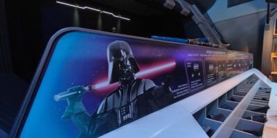 A vivid advertising panel featuring darth vader wielding a lightsaber inside a futuristic setting, with informational text and icons aligned on the side.