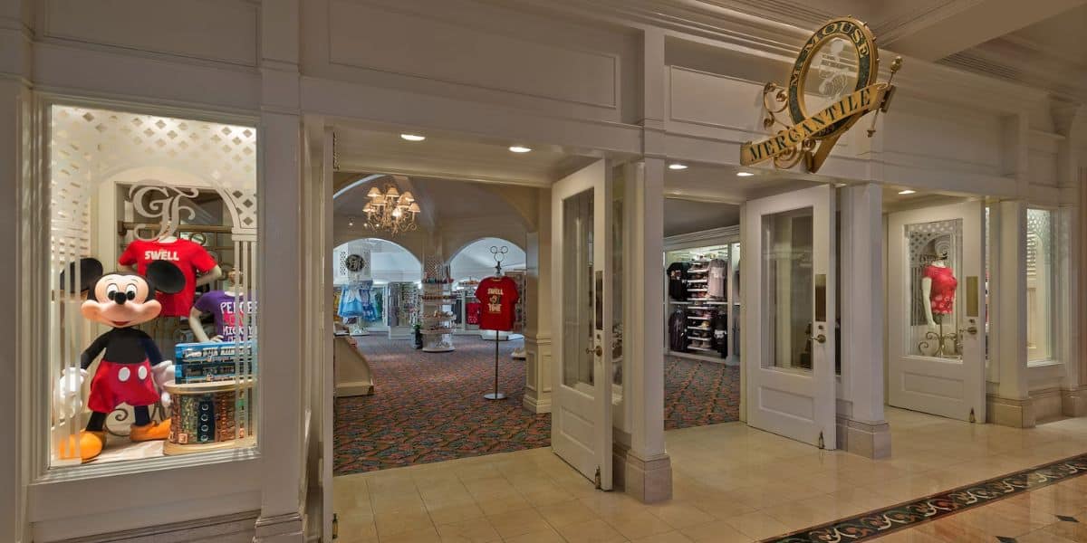 Interior of a disney store featuring a large mickey mouse plush toy near the entrance, with shelves of merchandise visible in the background. bright, welcoming atmosphere with themed decor.