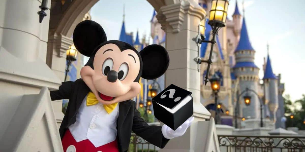 Mickey mouse holding a magic box in front of Cinderella's castle at Disney World.