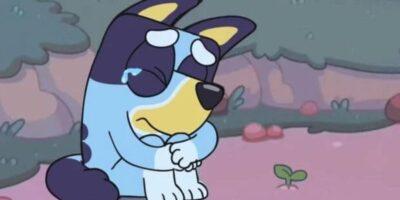 A cartoon image of Bluey, looking sad with tears in its eyes, sitting in a mystical pink-toned forest.