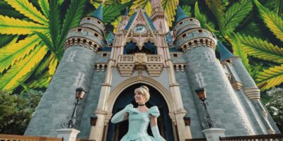 Cinderella posing in front of her Disney World castle surrounded by vibrant cannabis leaves.