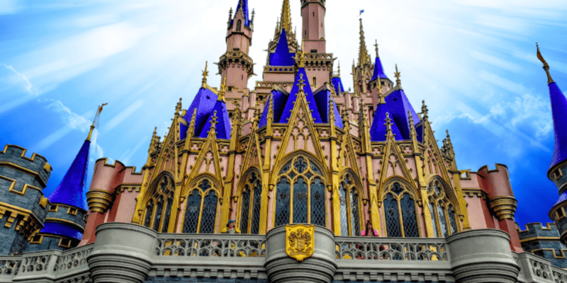 A vibrant image of a fairytale castle with tall spires, blue roofs, and intricate gothic architecture, set against a bright blue sky with radiant sunbeams.