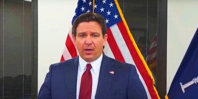 Ron DeSantis speaking at a podium, with the united states flag.