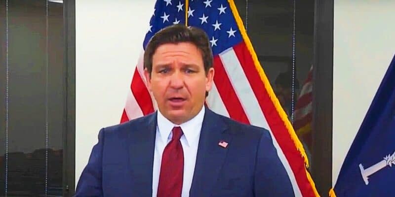 Ron DeSantis speaking at a podium, with the united states flag.