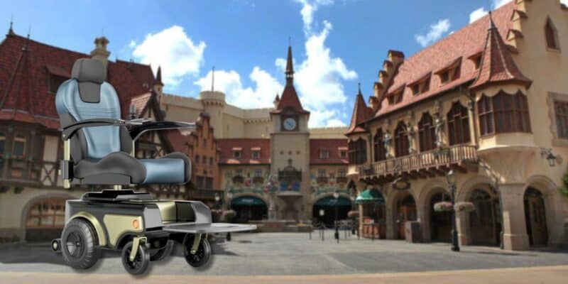 An image of an electric wheelchair with a modern design superimposed on a scenic european-style village square with traditional buildings and a central clock tower under a clear sky at EPCOT. This is the type of vehicle a woman in a Disney rental scooter tried to steal.