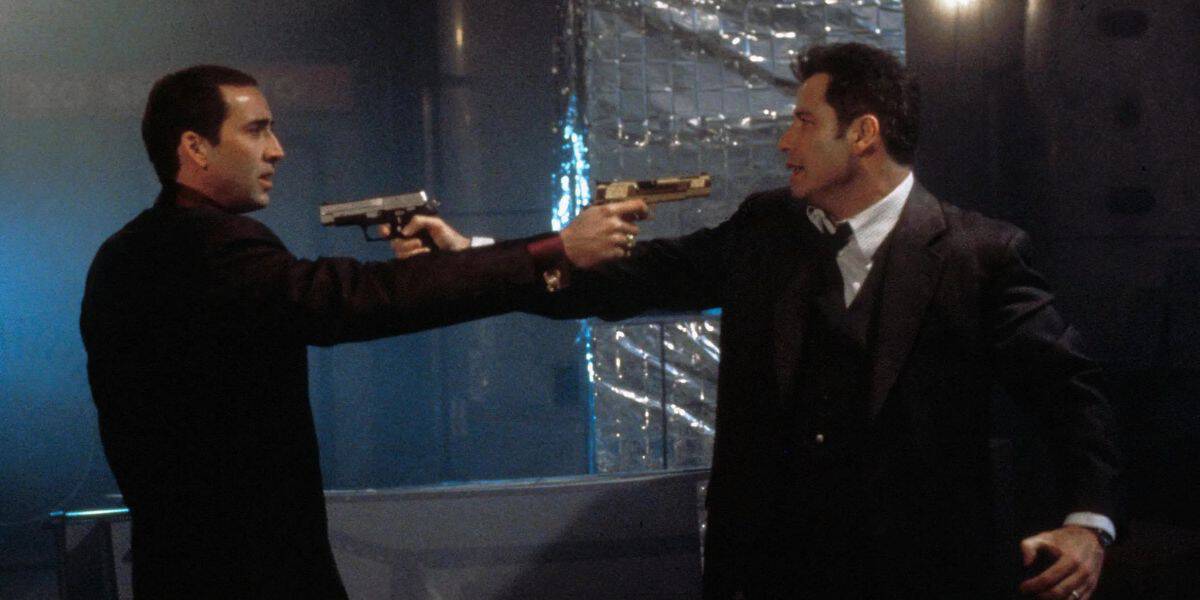Nicolas Cage (left) John Travolta (right) in Face/Off, suits pointing guns at each other.