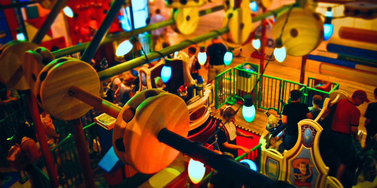 Overhead view of a colorful indoor amusement park with people enjoying various games and activities, showcasing bright lights and playful decor.
