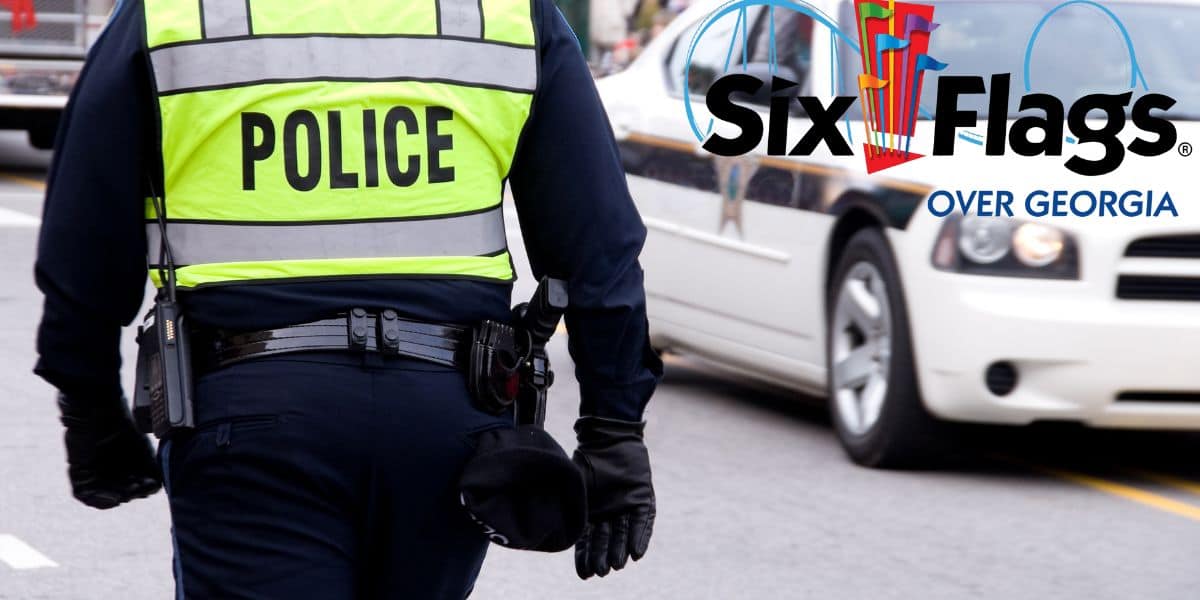 A police officer in reflective gear on duty near the road with a six flags over georgia sign in the background.
