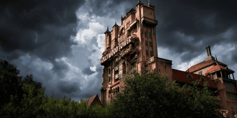 A dramatic image of Disney's Tower of Terror under a dark, stormy sky, accentuating its foreboding architectural details reminiscent of an old haunted mansion.