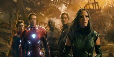The Avengers, including MCU stars Iron Man, Star-Lord, Drax, and Mantis, are grouped together and appear ready for battle in a chaotic, fiery landscape.