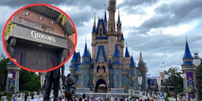 A bustling scene at Disney World features Cinderella Castle as the backdrop under a cloudy sky. The castle is adorned with blue and gold accents. An inset in the image highlights the entrance of Gideon's Bakehouse with its sign prominently displayed, amidst whispers of employee accusations.