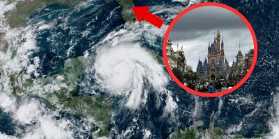 A satellite image shows a large hurricane over the Gulf of Mexico approaching the southeastern United States. An inset photo, highlighted with a red circle and arrow, depicts a crowded day at Disney World with its prominent castle under cloudy skies.