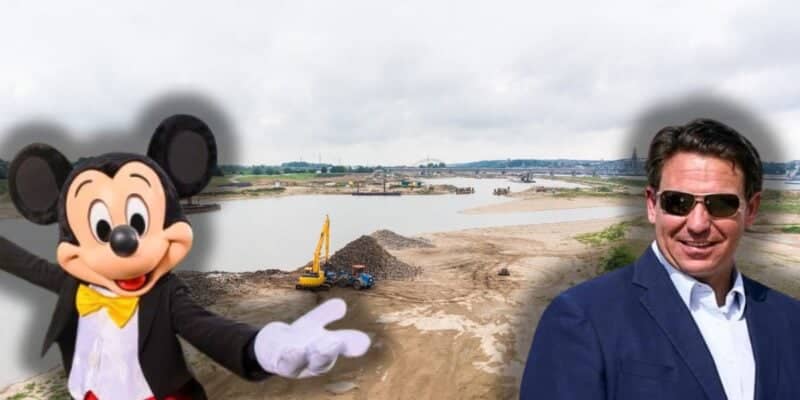 A construction site near a body of water is shown. An animated character, Mickey Mouse, stands on the left side, while a man resembling DeSantis in a suit and sunglasses is on the right. Both have a blurred effect, making them appear superimposed onto the background.