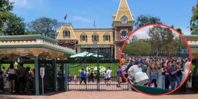 A busy entrance to Disneyland with a crowd of visitors walking through the gates. A red circle highlights an even larger, dense crowd of people in another section of the park, showcasing a bustling day at the theme park.