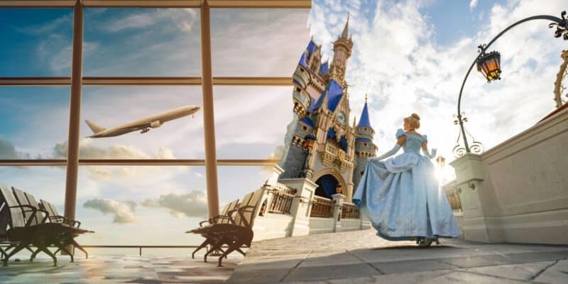 A woman dressed as Cinderella at a Disney theme park with a castle in the background, viewed from a sunlit patio with chairs, as a plane flies overhead in a clear sky.