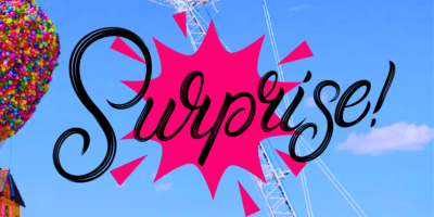Colorful image featuring the word "Surprise!" in bold, black script inside a pink starburst graphic against a blue sky. A ferris wheel and a cluster of multicolored balloons reminiscent of an UP-Inspired Airbnb are visible in the background.