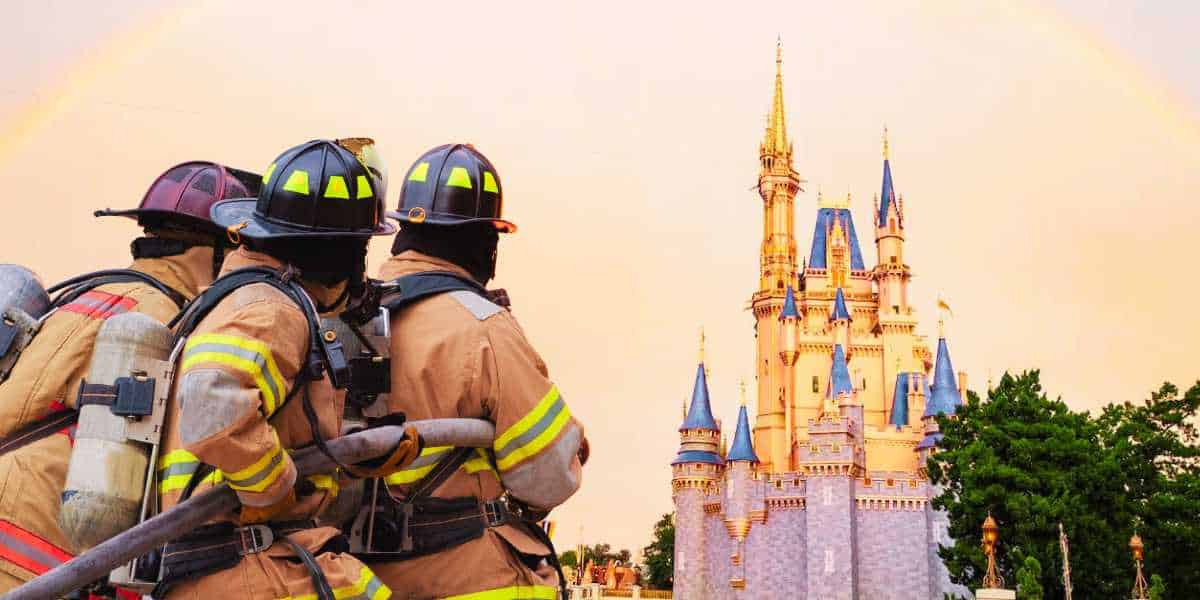Firefighters in gear observing a scene, with a whimsical castle and a rainbow in the background, suggesting a Disney World location.