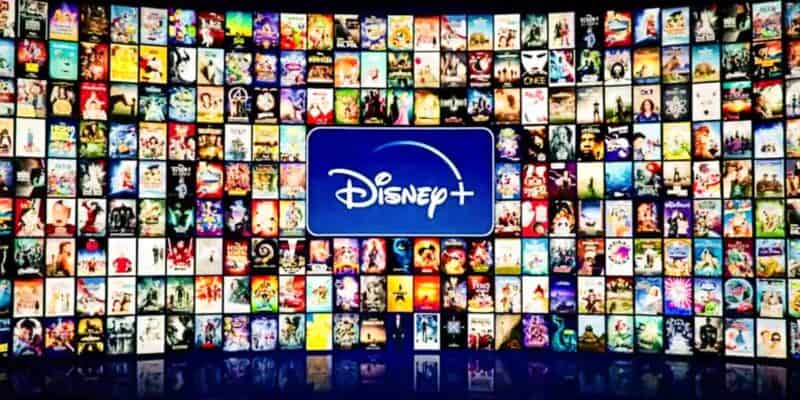 A large collage of various Disney+ movie and TV show posters displayed in a semicircular shape, with a prominent Disney+ logo in the center. The posters feature a wide range of animated and live-action content available on the streaming platform.