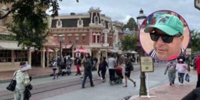 Guests walking down Main Street, U.S.A. at Disneyland. In the foreground is a screenshot from a video of a man discussing the Disney filming crackdown.
