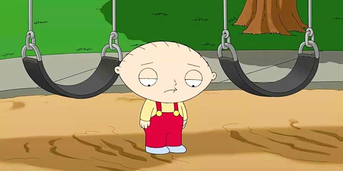 Cartoon image of Stewie Griffin with a bald head, wearing a yellow shirt and red overalls, standing between two swings in a playground, looking slightly sad or thoughtful.