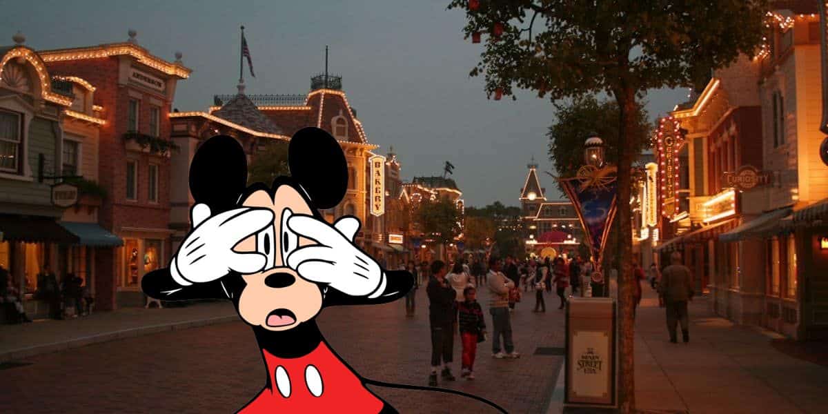 Illustration of Mickey standing in front of a bustling street scene at Disney Park with lights and buildings, covering his eyes with his hands in an exaggerated pose.