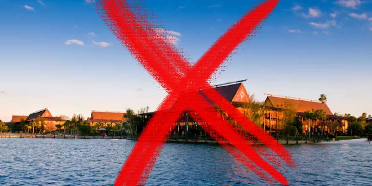 Lake view of the Magic Kingdom Polynesian Resort with large buildings at sunset, overlaid with a large red 'X' mark.