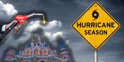 A composite image shows a hand holding a fuel pump nozzle with a drop of fuel, a fanciful castle in the background, and a yellow traffic sign with the words "Hurricane Season" and a hurricane symbol next to it under a cloudy, dark sky reminiscent of a Ron DeSantis storm warning for Disney World.