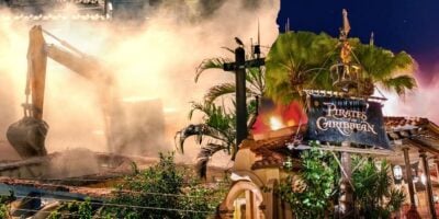 A split image shows a construction site on the left with heavy machinery and dust in the air. On the right is the entrance to Disney's "Pirates of the Caribbean" attraction, featuring a sign surrounded by tropical foliage and illuminated by night-time lighting.