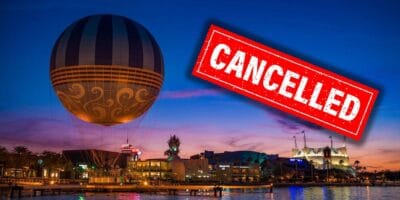 A large hot air balloon is tethered above an illuminated cityscape at dusk, featuring various buildings and water in the foreground. A prominent red "Cancelled" stamp overlays the right side of the image, reminiscent of a night out at Disney Springs cut short.
