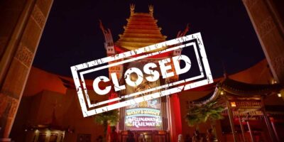 The image shows an entrance to a theater-like building with Chinese architectural elements. A large "CLOSED" stamp overlays the entrance, which includes a sign for "Mickey & Minnie's Runaway Railway." The scene, reminiscent of Disney World, is illuminated, possibly at night, restricting guest access.