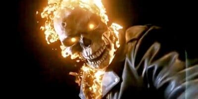 A flaming skull character with fiery eyes and a wide-open mouth, wearing a dark leather jacket, is shown against a dark background. Flames are emanating from the character's head and shoulders, creating an intense and dramatic visual effect.