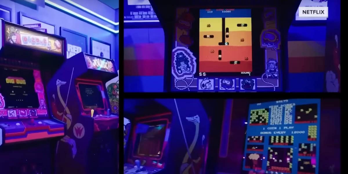 A retro arcade gaming area with brightly-lit game machines. The image captures close-ups of three arcade screens: one displaying "Dig Dug," another with classic pixelated gameplay, and a larger screen showcasing a multi-level game. The Netflix logo is visible.