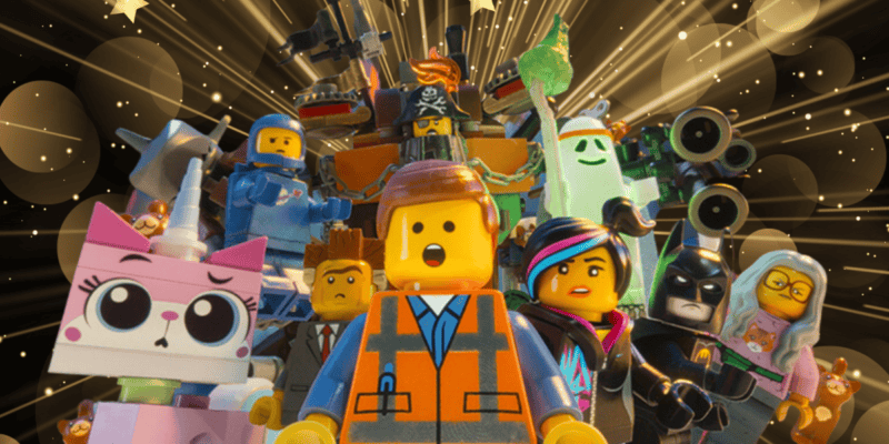 A group of colorful LEGO characters, including a construction worker, a cat-like creature, Batman, and others, stand together looking ahead. Behind them are glowing, golden starburst patterns that add to the vibrant and dynamic feel. Two arrested suspects were allegedly involved in the theft of stolen LEGO sets nearby.