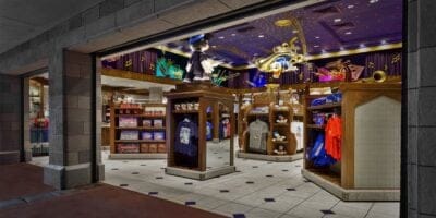 A vibrant store interior filled with colorful merchandise themed around popular characters. Shelves display clothing, plush toys, and various souvenirs. The ceiling features playful decor, and a large character statue is prominently positioned near the entrance.