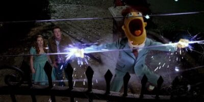 A Muppet character in a suit is getting electrocuted on a fence.